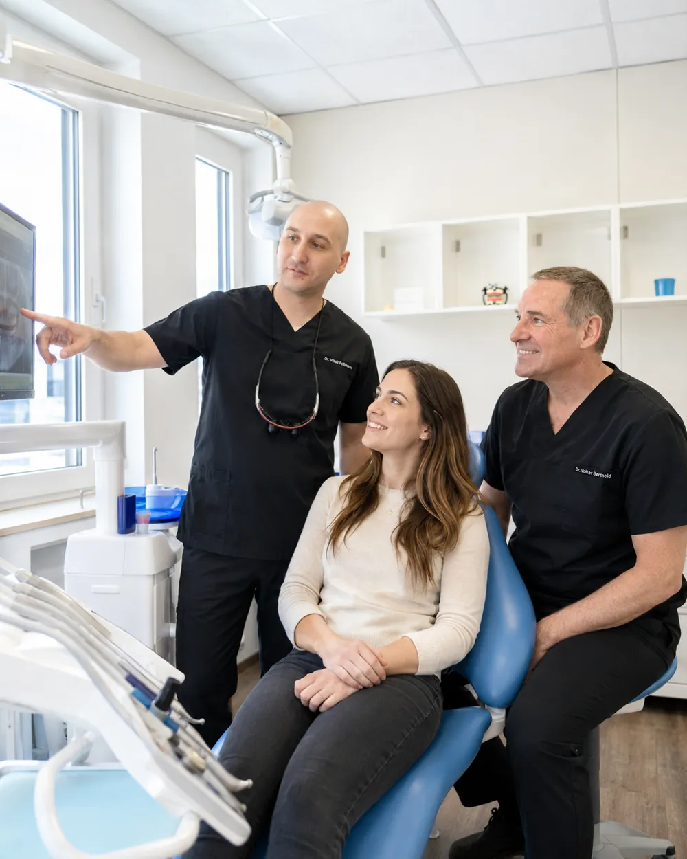 Zwei Zahn&auml;rzte besprechen Aufnahmen mit einer Patientin, Praxisklinik Dr. Fellmann & Kollegen in Dortmund